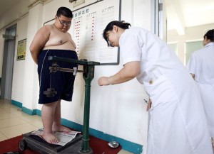 A 16-year old boy weighing 138 kg stands on the scale as a nurse documemts his weight